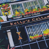 Close-up of Kelly’s Cellar illustration showing the pub sign, black doorway and flower-filled windows.